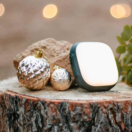 A Lander lantern sits atop a stump, surrounded by Christmas tree ornaments